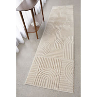 Beige patterned rug on a light gray floor with a wooden side table.
