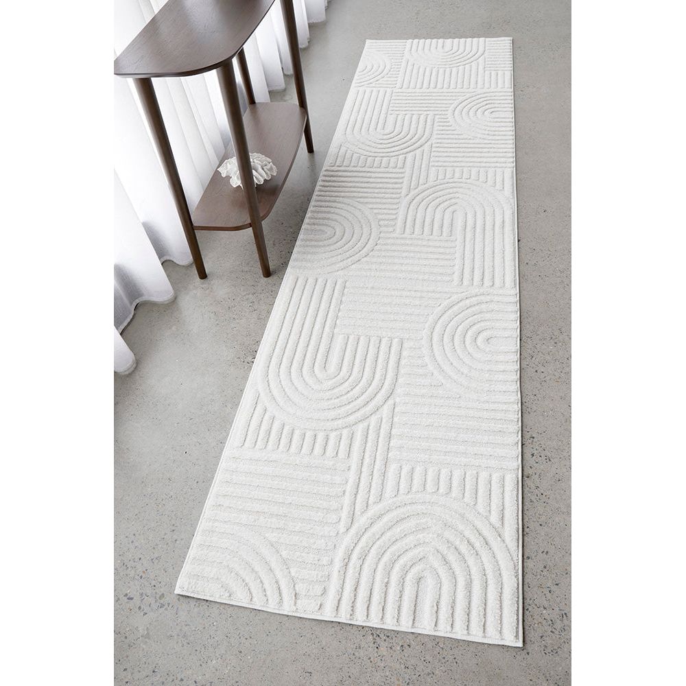 White textured runner rug on a gray floor with a wooden side table.