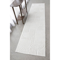 White textured runner rug on a gray floor with a wooden side table.
