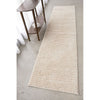 Beige runner rug on a concrete floor with a wooden side table.