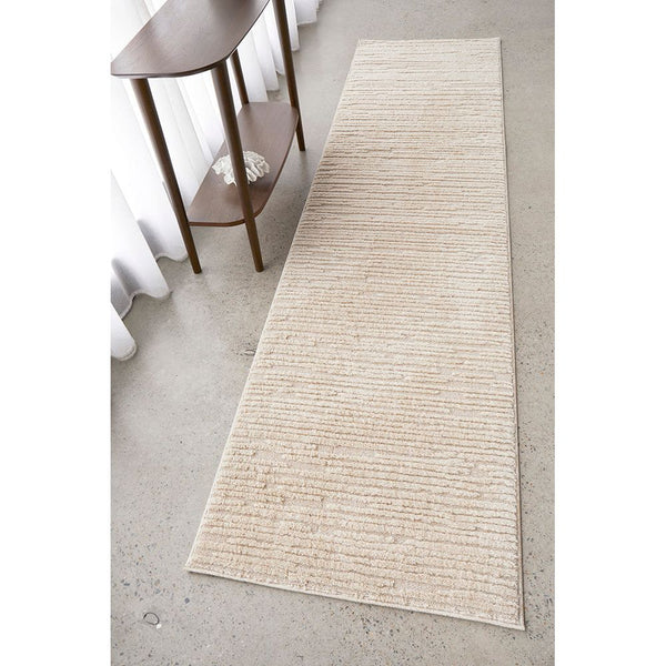 Beige runner rug with subtle textured linear pattern on concrete floor near wooden console table.