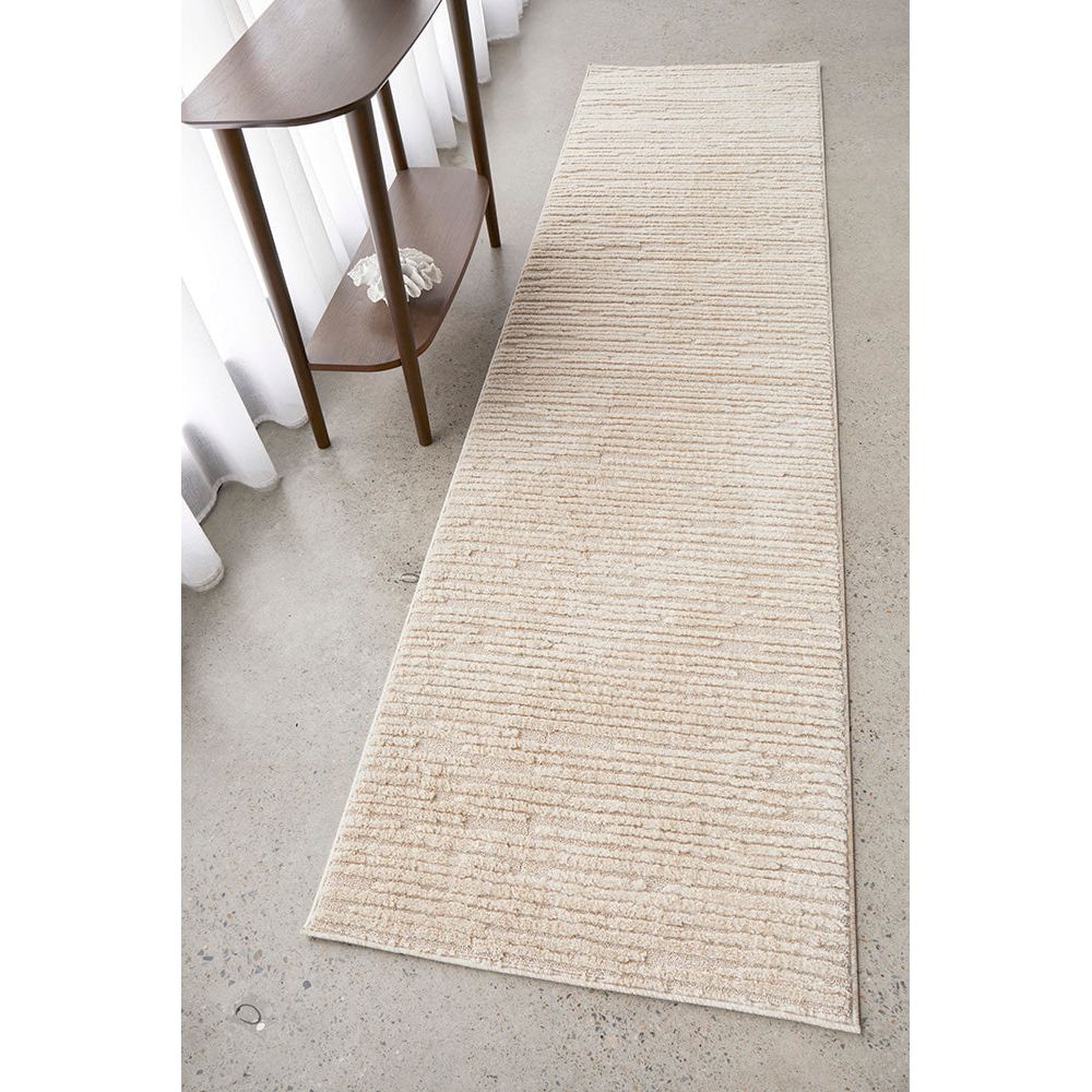 Beige runner rug on a concrete floor with a wooden side table.