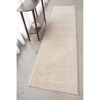 Beige runner rug on a concrete floor with a wooden side table.
