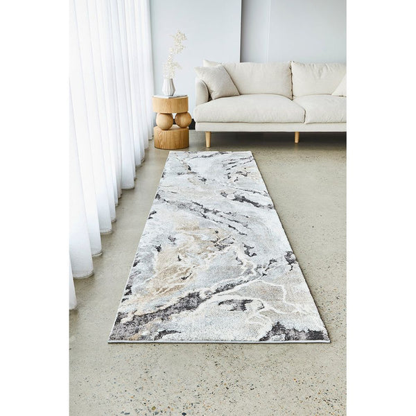 Natural multi-colored abstract patterned runner rug in soft neutral tones on polished concrete floor.