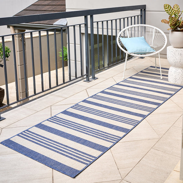 Blue and white striped flatweave runner rug on outdoor tiled balcony floor.