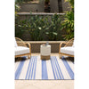 Outdoor seating area with two wicker chairs and a small table on a blue and white striped rug.