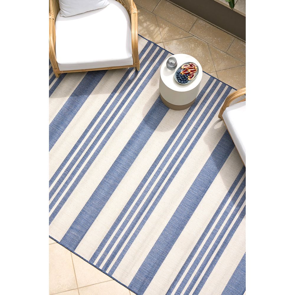 Blue and white striped rug on a tiled floor with a chair and small table.
