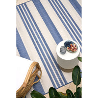 Blue and white striped rug with a small table and decorative items on a tiled floor.