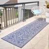 Blue patterned outdoor runner rug on a patio with a chair and plants.