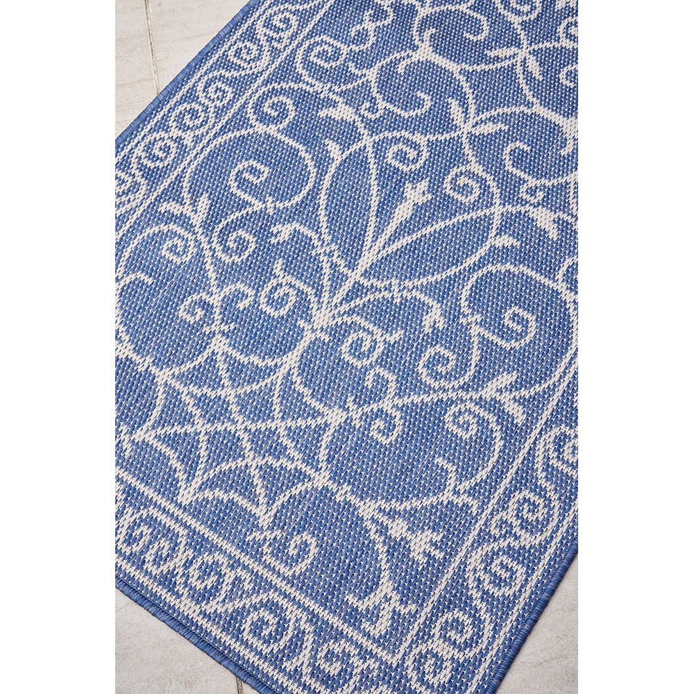 Blue and white patterned runner rug on a tiled outdoor area.
