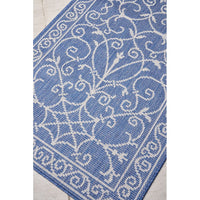 Blue and white patterned runner rug on a tiled outdoor area.