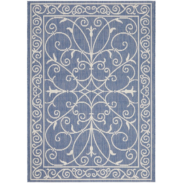 Blue indoor outdoor rug with intricate white modern floral and swirl pattern, flat-weave texture.