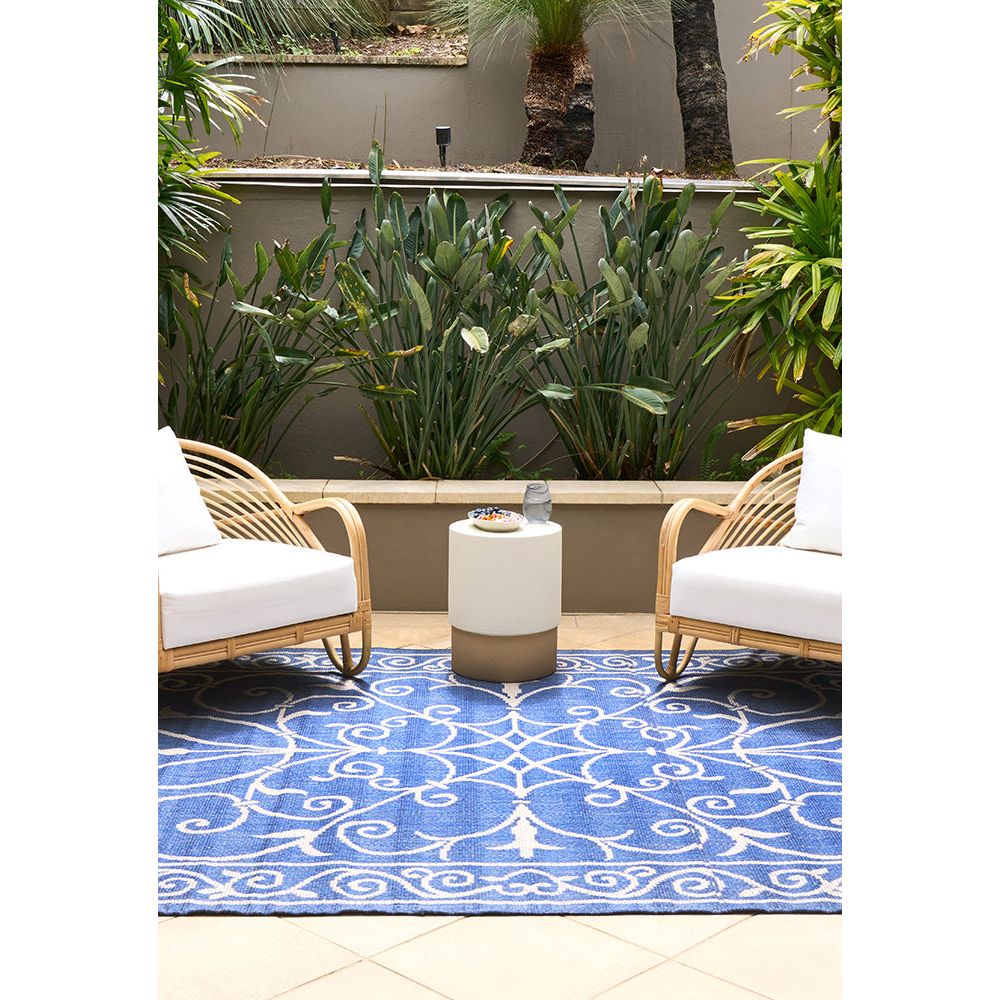Outdoor patio with wicker chairs, a small table, and a blue patterned rug.