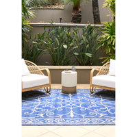 Outdoor patio with wicker chairs, a small table, and a blue patterned rug.