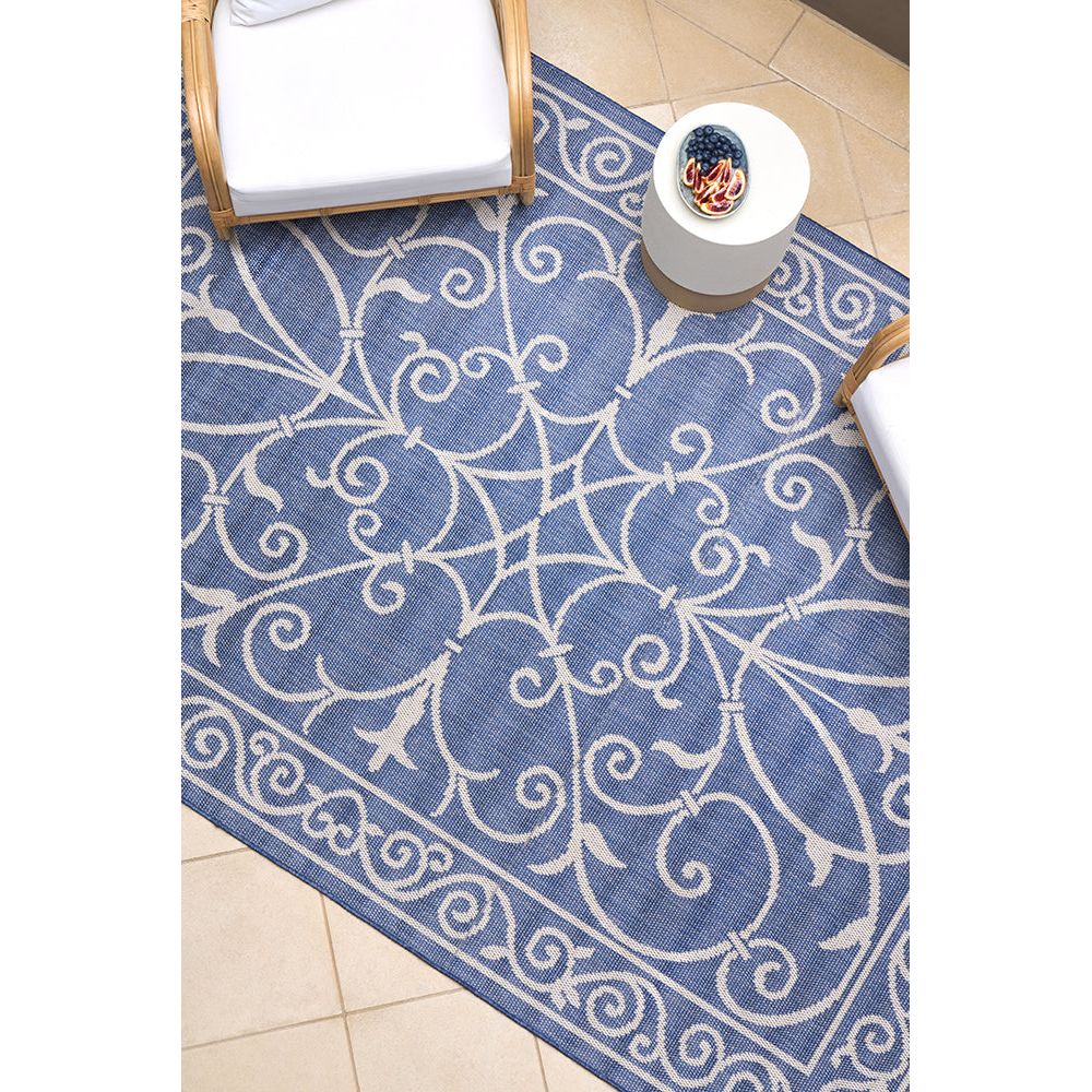 Blue and white patterned outdoor rug on a tiled floor.