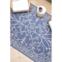 Blue and white patterned outdoor rug on a tiled floor.