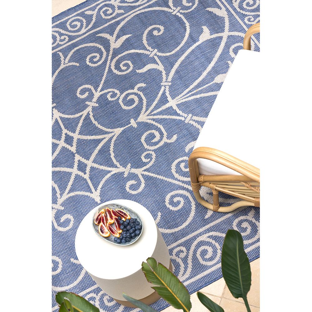 Decorative blue and white patterned rug with a bowl of fruit on a tiled surface.