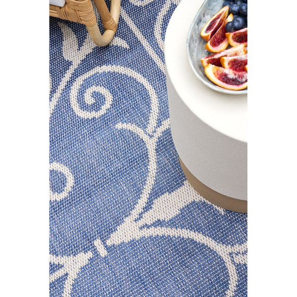 Blue Northcliffe 406 indoor outdoor rug with white modern swirling pattern under white round table.