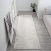 Light grey runner rug with subtle geometric texture on light wood floor in bright hallway.