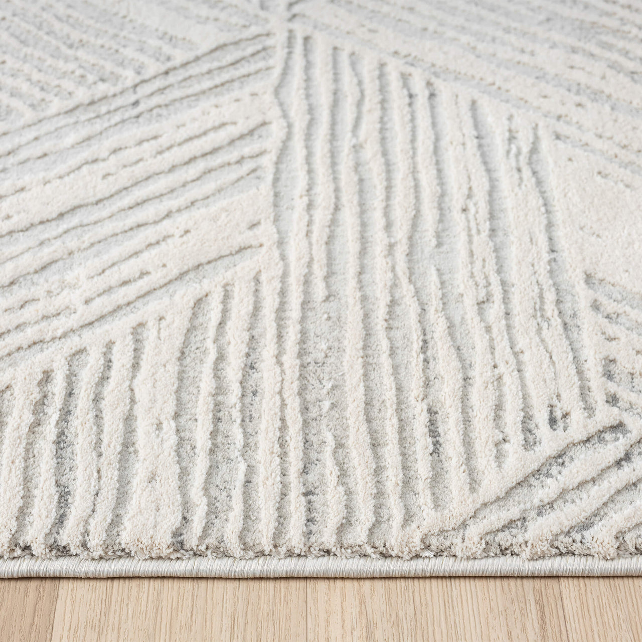 Light grey modern runner rug with raised geometric textured pattern and soft pile on wood floor.