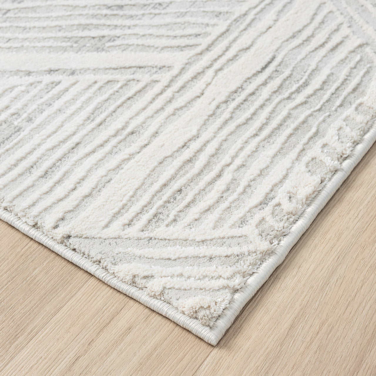 Light grey modern rug with geometric textured pattern and soft pile on wooden floor.