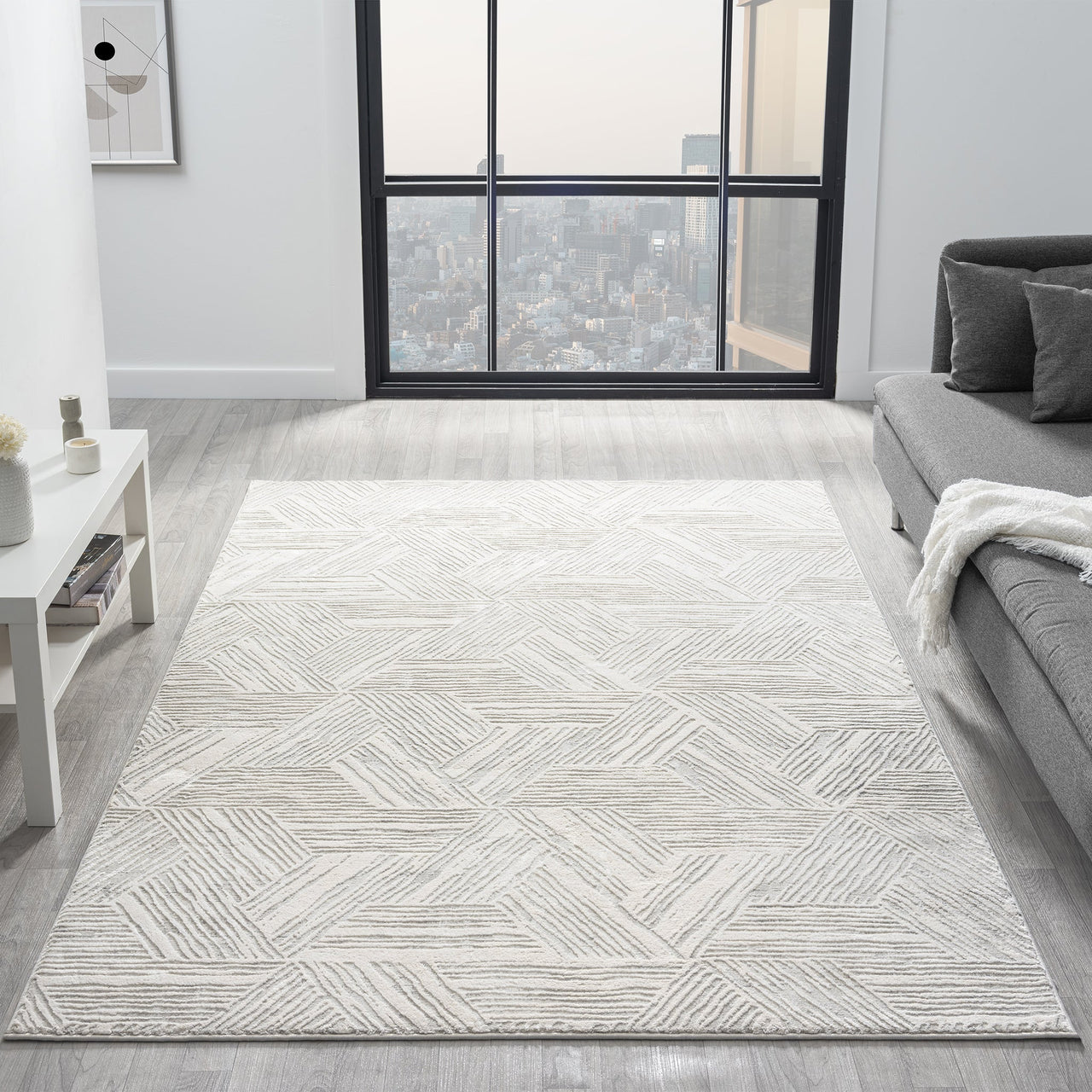 Light grey modern rug with subtle geometric textured pattern in a spacious, minimalist living room.