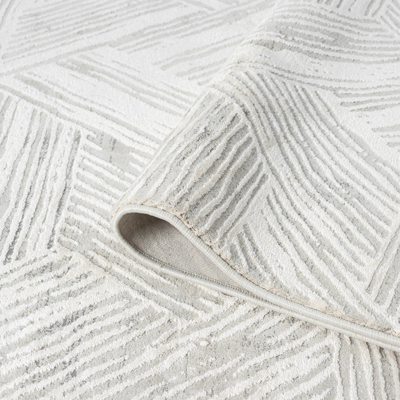Light grey rug with geometric textured pattern and subtle raised pile detail.