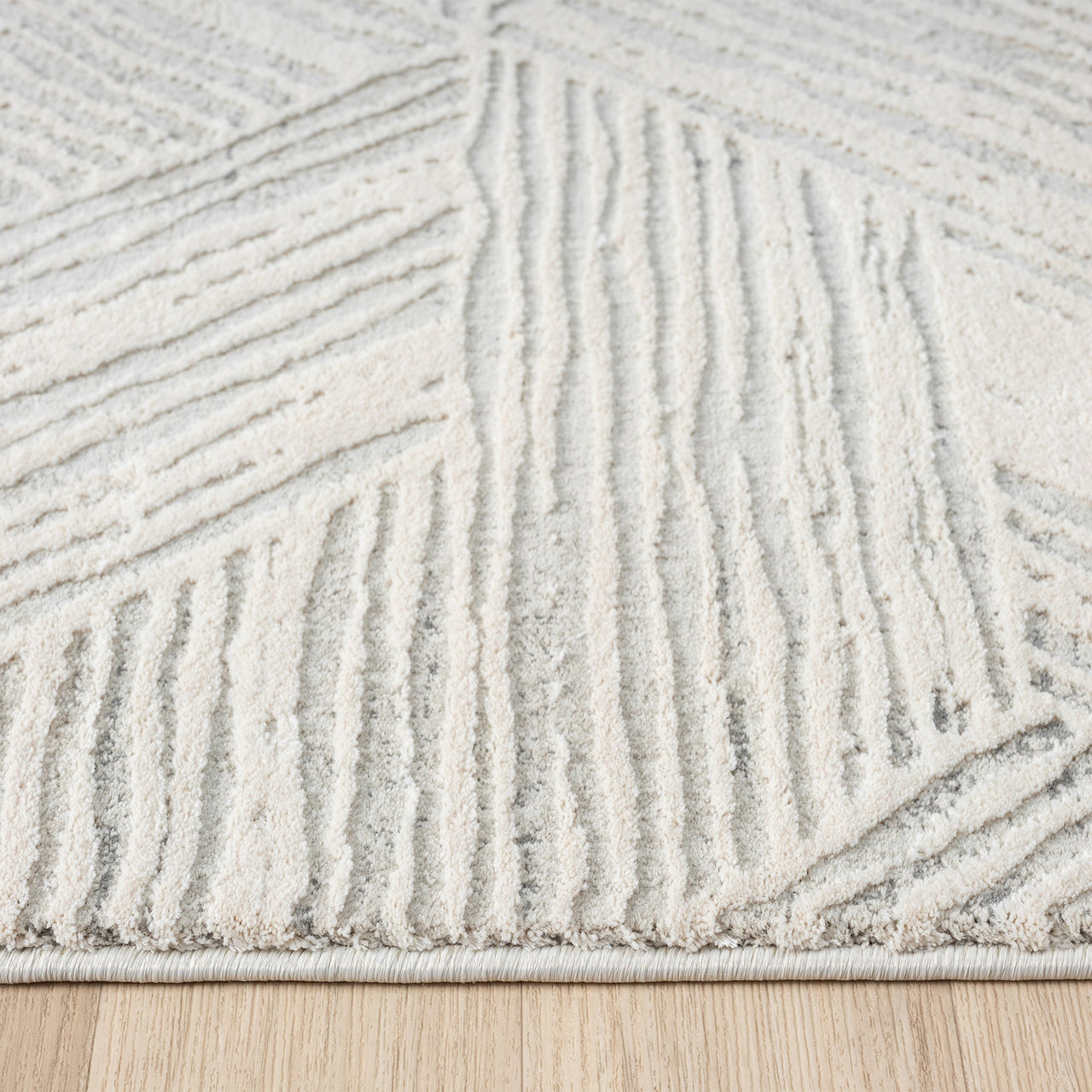 Light grey modern rug with geometric textured patterns and raised pile on neutral background.