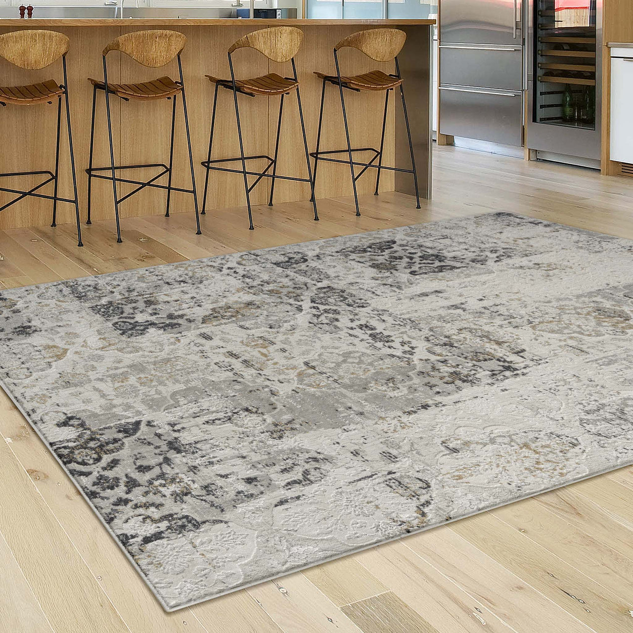 Grey multi-color abstract textured rug with patchwork design on light wood floor.