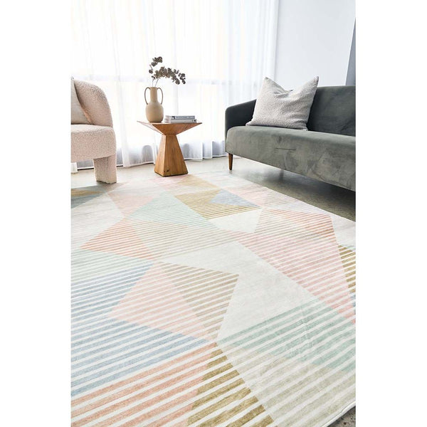 Pastel geometric patterned rug with soft pink, blue, beige, and green hues in modern living room setting.