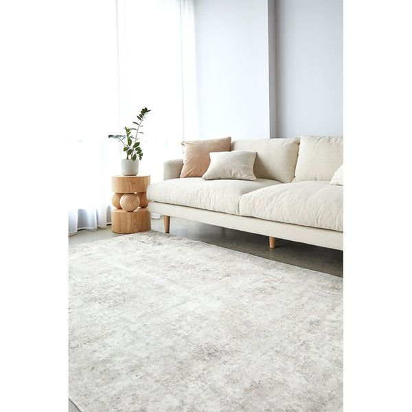 Neutral-toned marble pattern rug with soft texture under a modern beige sofa in a bright room.
