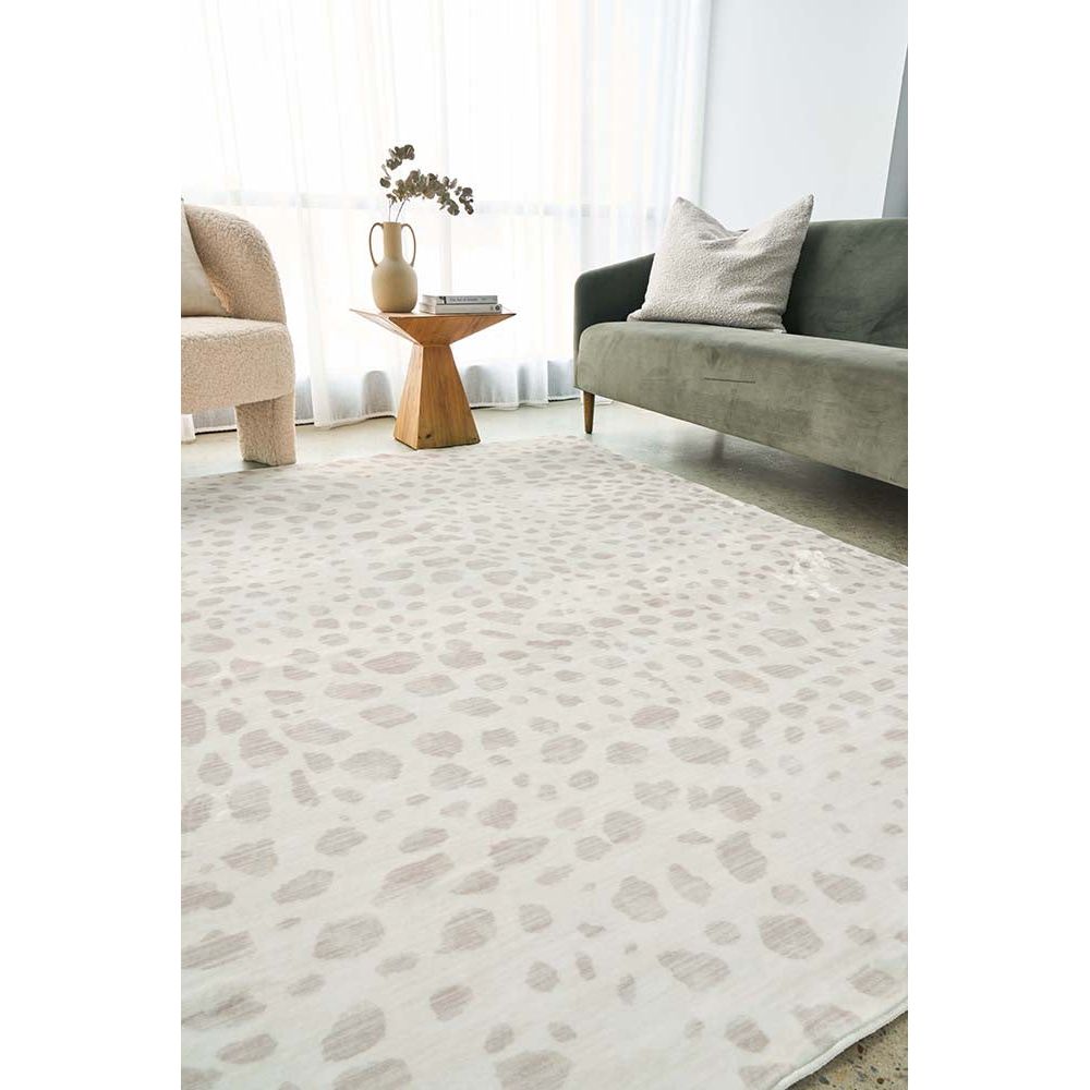 Neutral-toned modern rug with subtle abstract pattern, placed in minimalist living room with green velvet sofa and wooden.