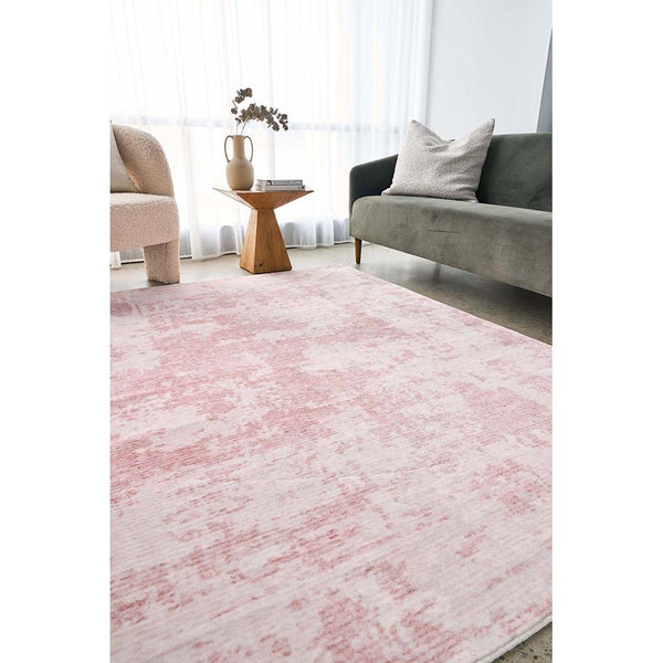 Blush pink modern patterned rug with subtle texture in a bright living room setting.