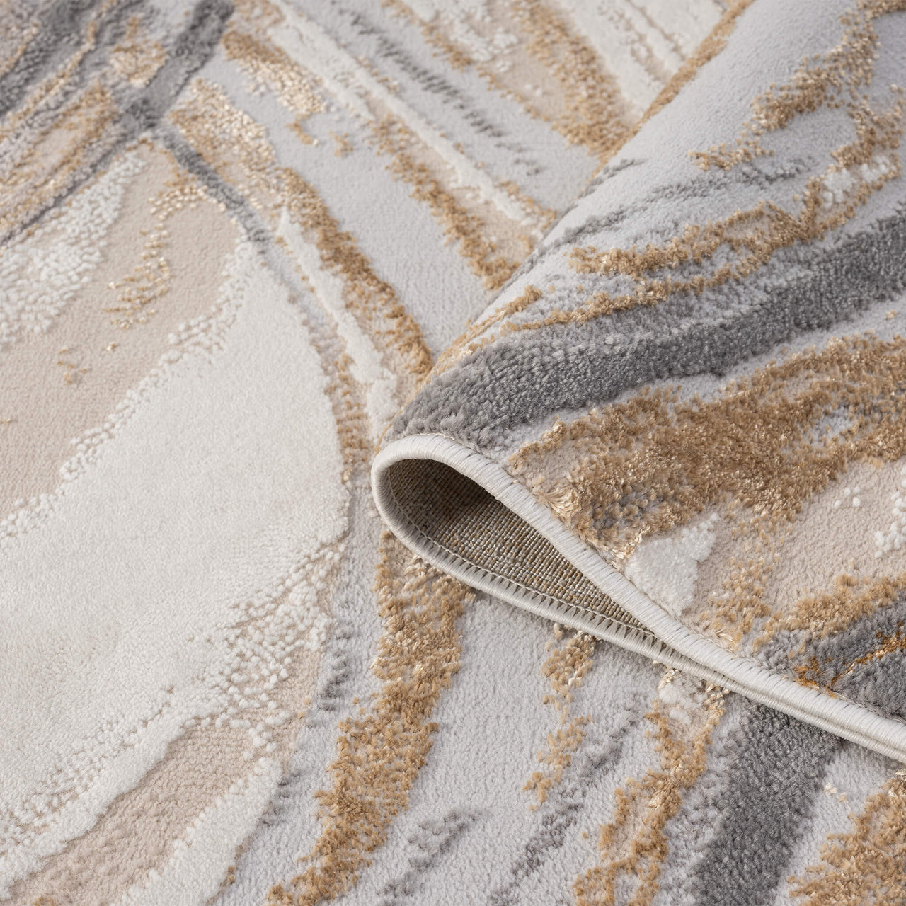 Beige modern rug with abstract wavy pattern in shades of cream, tan, and gray, folded corner showing texture.