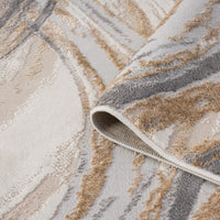 Beige modern rug with abstract wavy pattern in shades of cream, tan, and gray, folded corner showing texture.