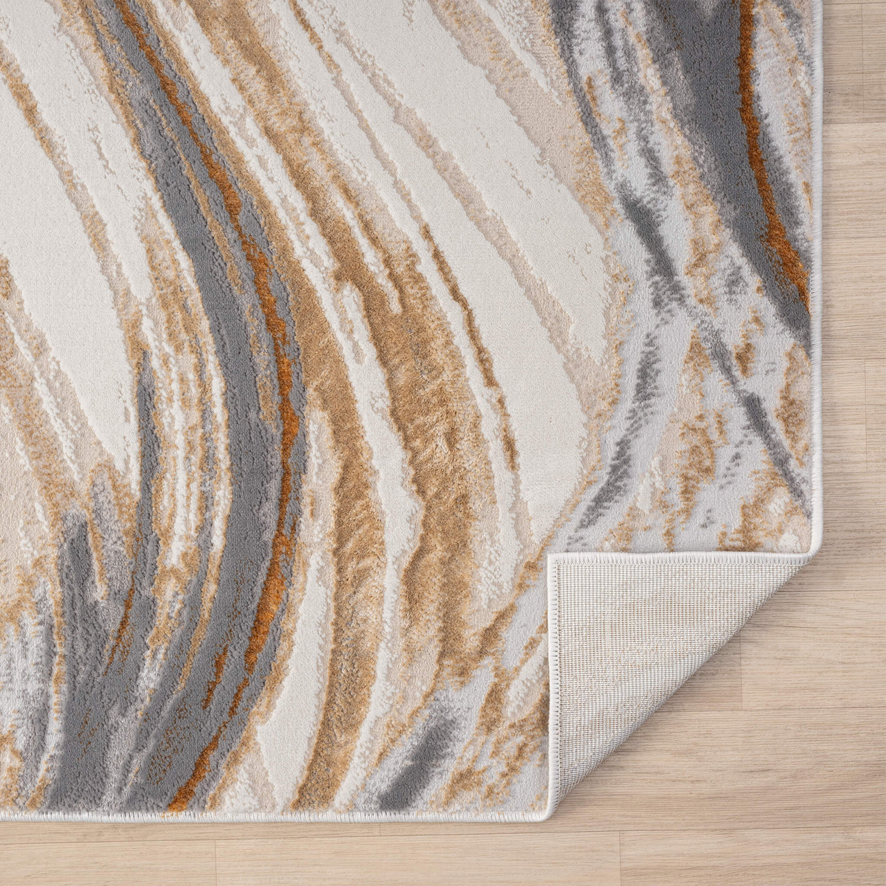 Beige modern rug with abstract wavy pattern in grey, white, and brown tones on wood floor.