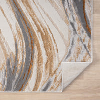 Beige modern rug with abstract wavy pattern in grey, white, and brown tones on wood floor.