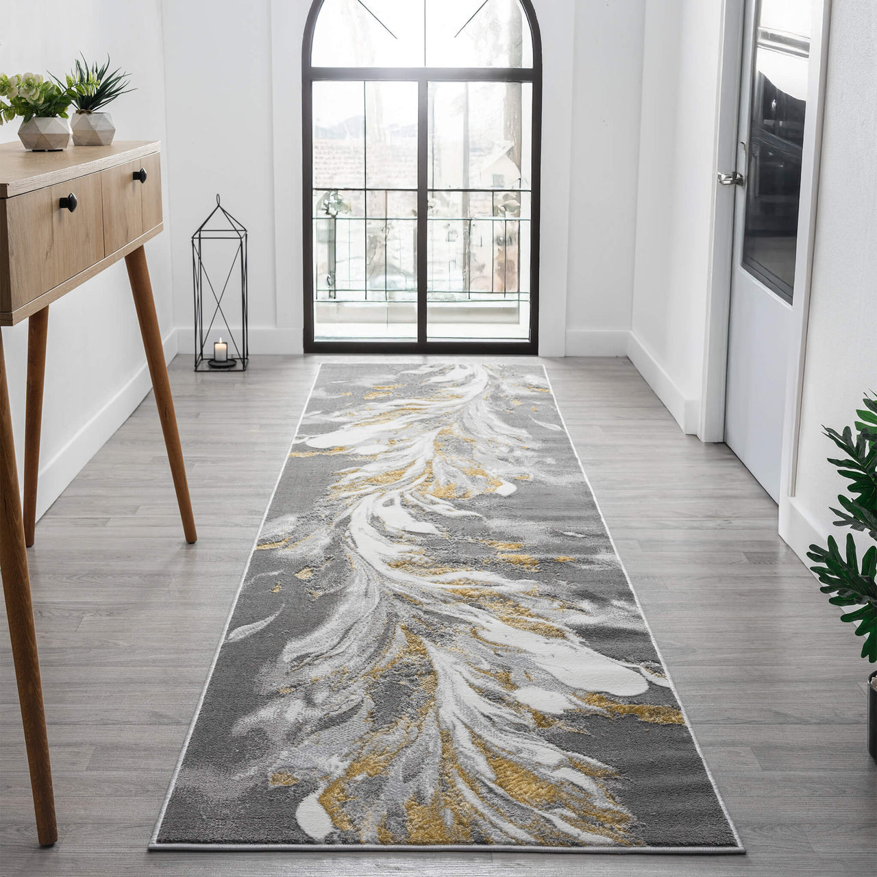 Grey runner rug with abstract swirling white and gold patterns on a modern hallway floor.