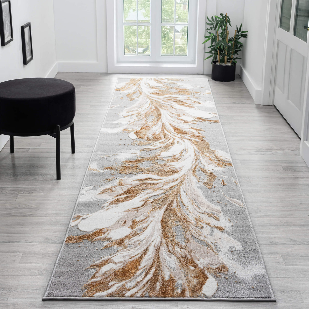 Beige and gold abstract patterned runner rug on light hardwood floor in bright hallway.