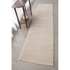 Beige runner rug on a light gray floor with a wooden side table.