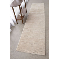 Beige runner rug on a light gray floor with a wooden side table.