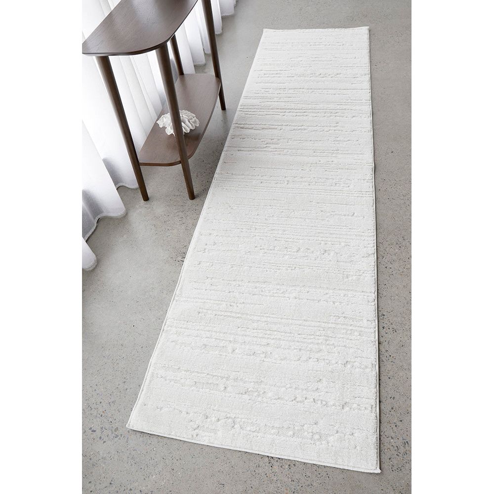 White textured runner rug on a gray floor with a wooden side table.