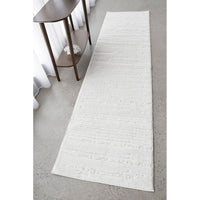 White textured runner rug on a gray floor with a wooden side table.