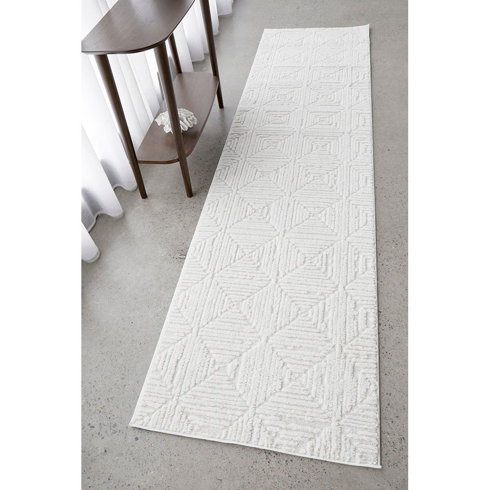 White textured runner rug on a gray floor with a wooden side table in the background.