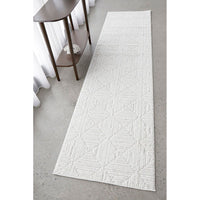 White textured runner rug on a gray floor with a wooden side table in the background.