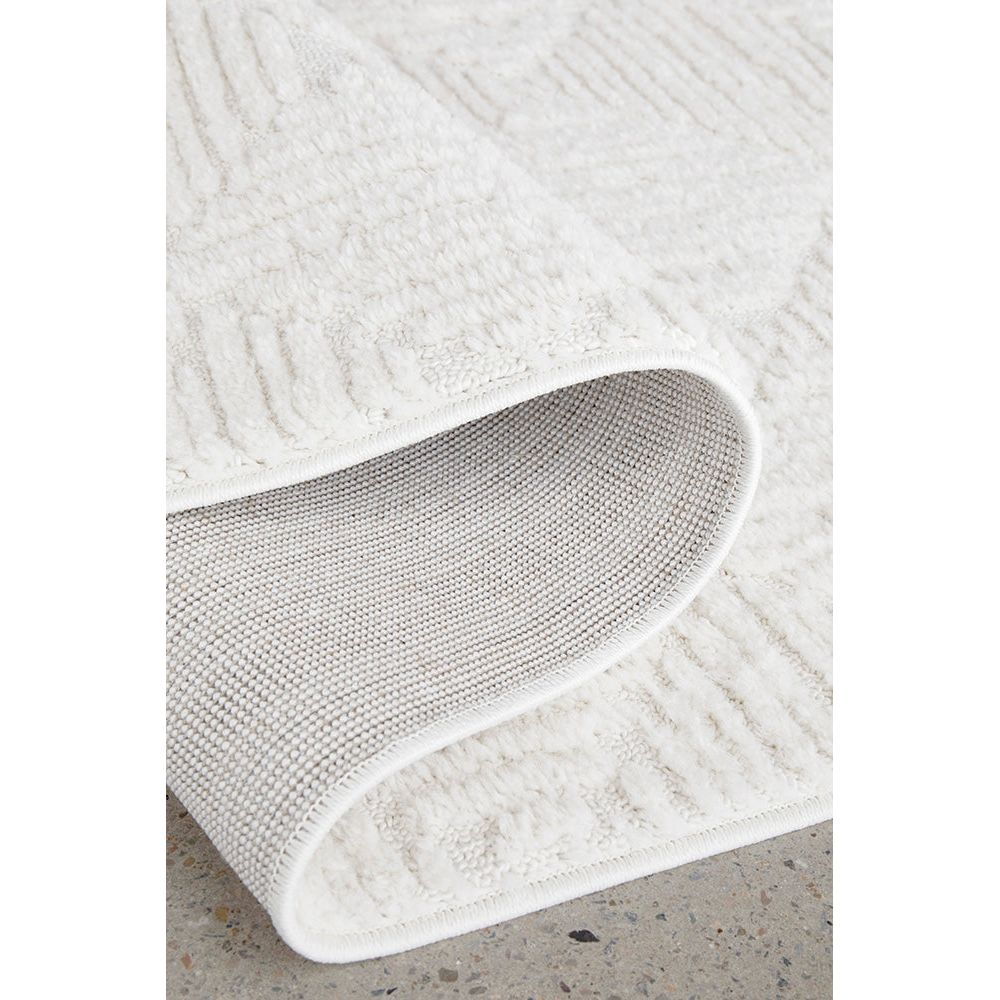 Close-up of a textured white rug on a concrete floor