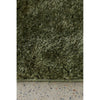 Close-up of a green shaggy rug on a concrete  floor.