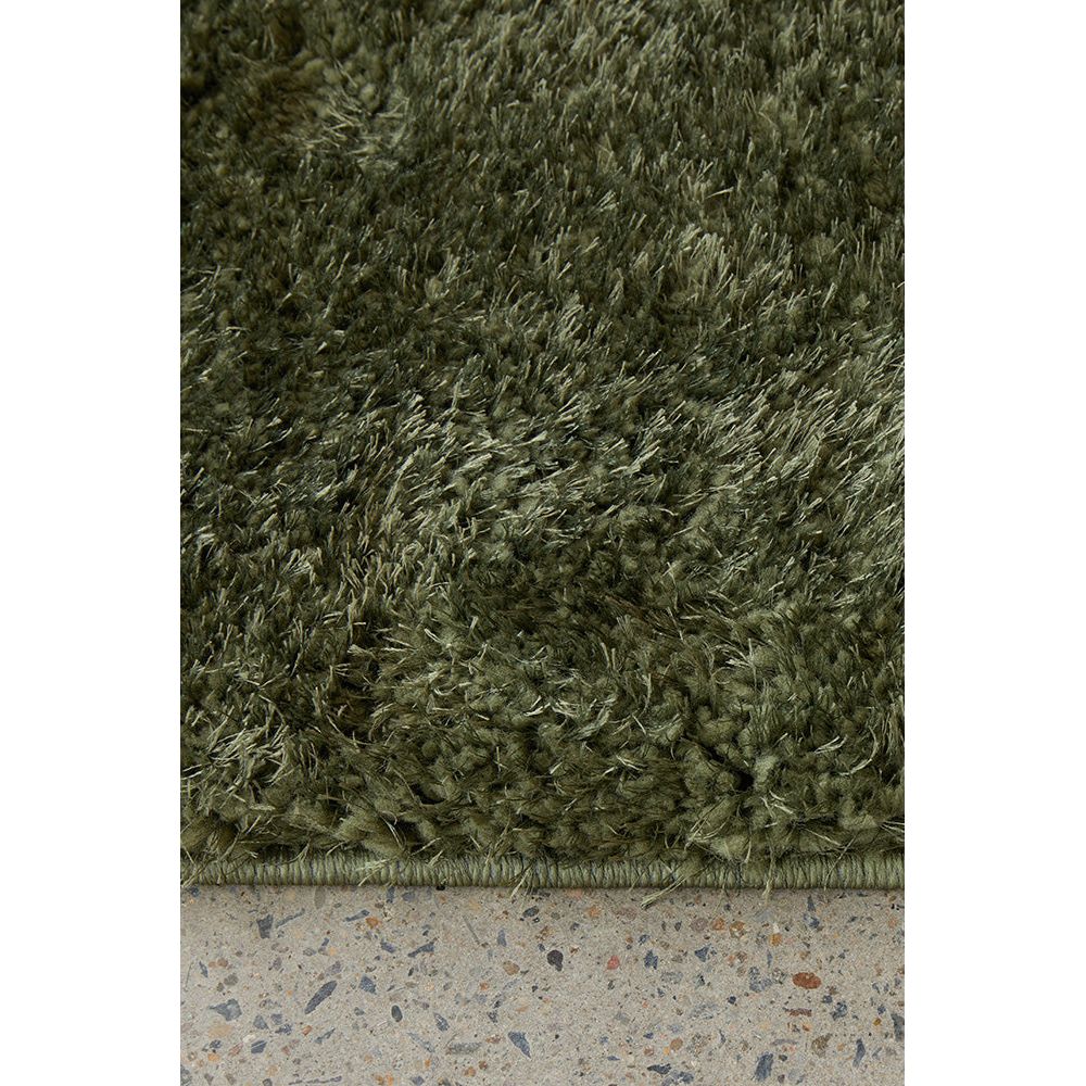 Close-up of a green shaggy rug on a concrete  floor.