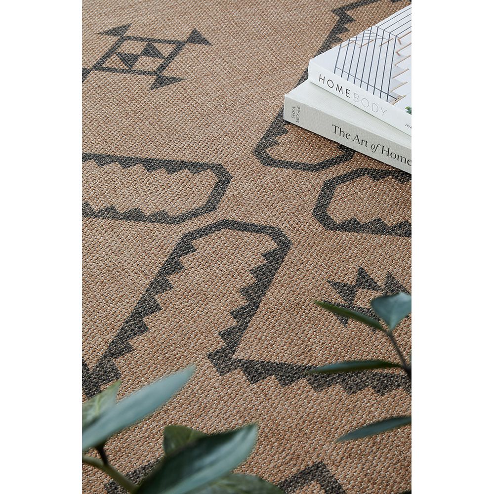 Patterned rug with geometric designs and a book and plant on top.