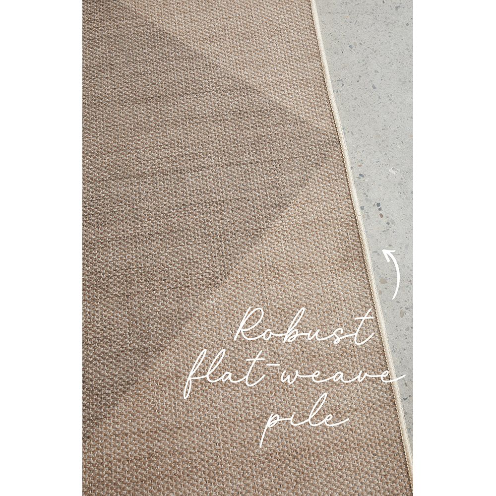 Textured brown rug with robust flatweave pile text on a concrete floor.